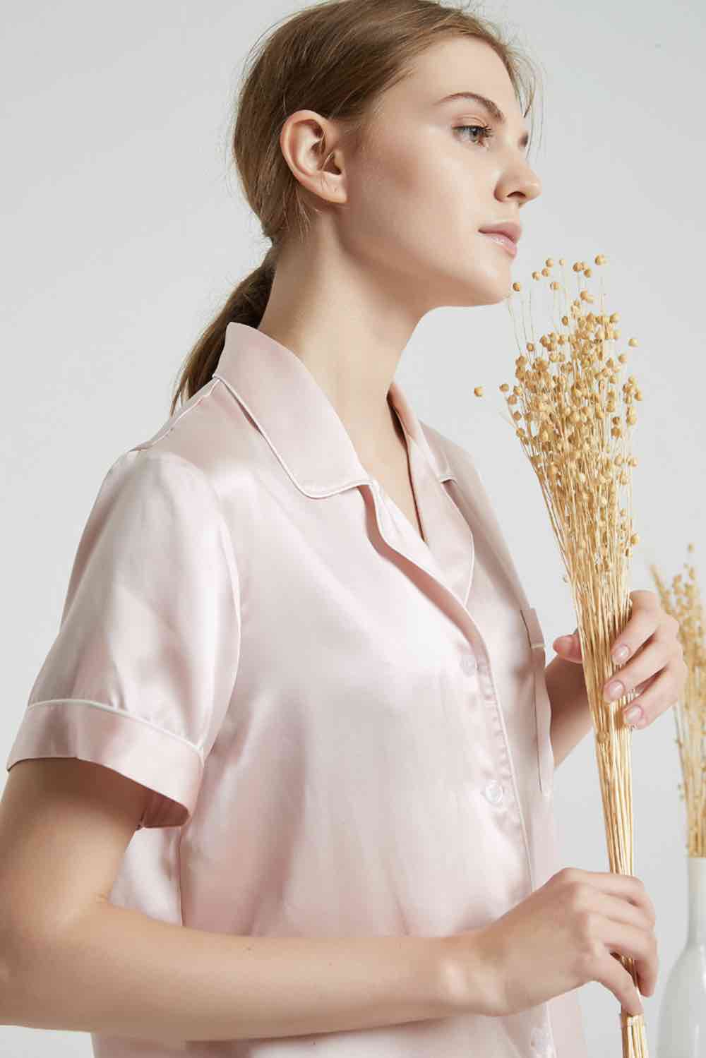 Woman in a pale pink short-sleeve pyjama top holding dried flowers