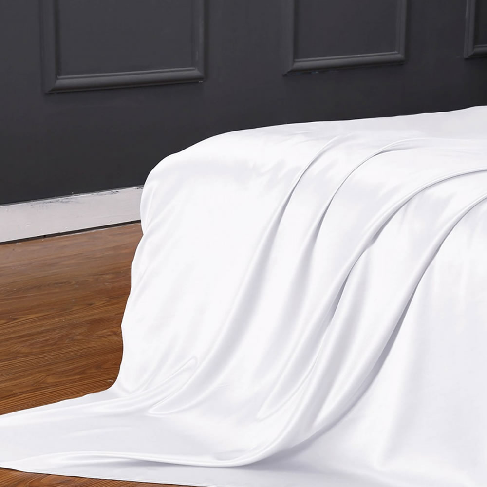 White silk sheet draped over the end of a bed