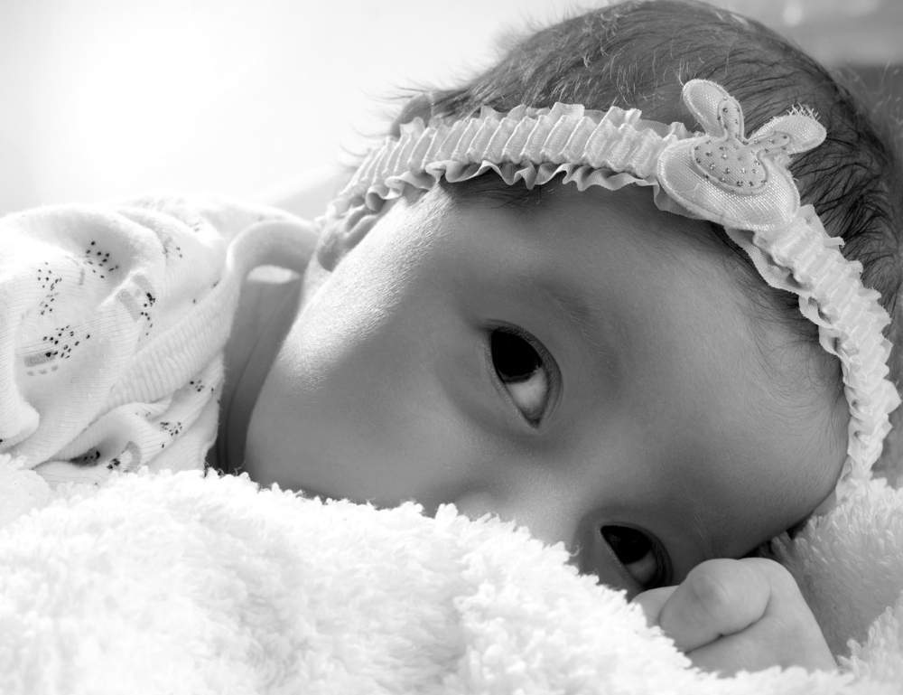 Black and white photo of a baby lying on a soft blanket